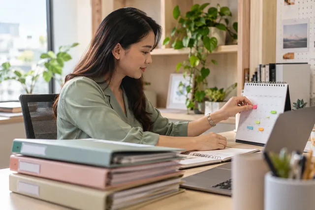 A coordinator schedules monthly client tasks on a planner.